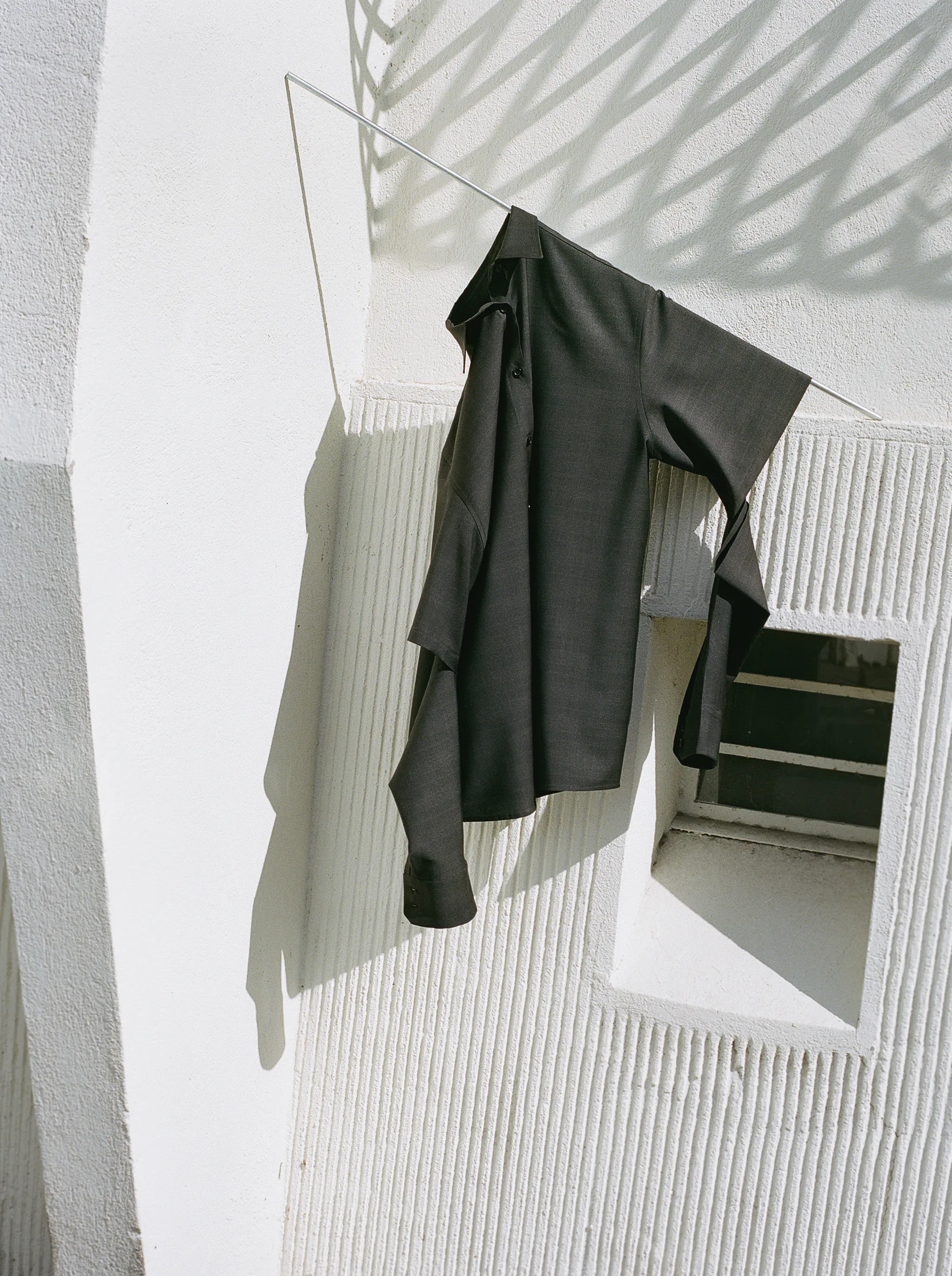 Black Drop 3 shirt displayed against a sunlit wall